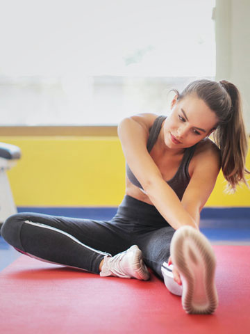 Woman stretching on a gym floor during a workout.