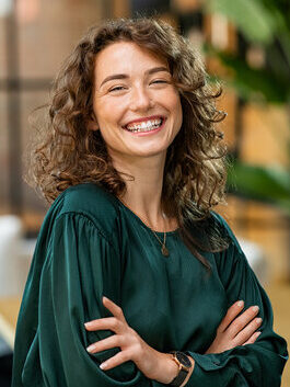 Smiling woman standing indoors with arms crossed.