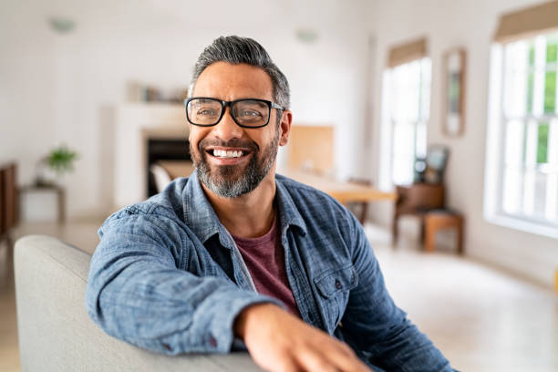 Smiling man seated comfortably in a bright living space.